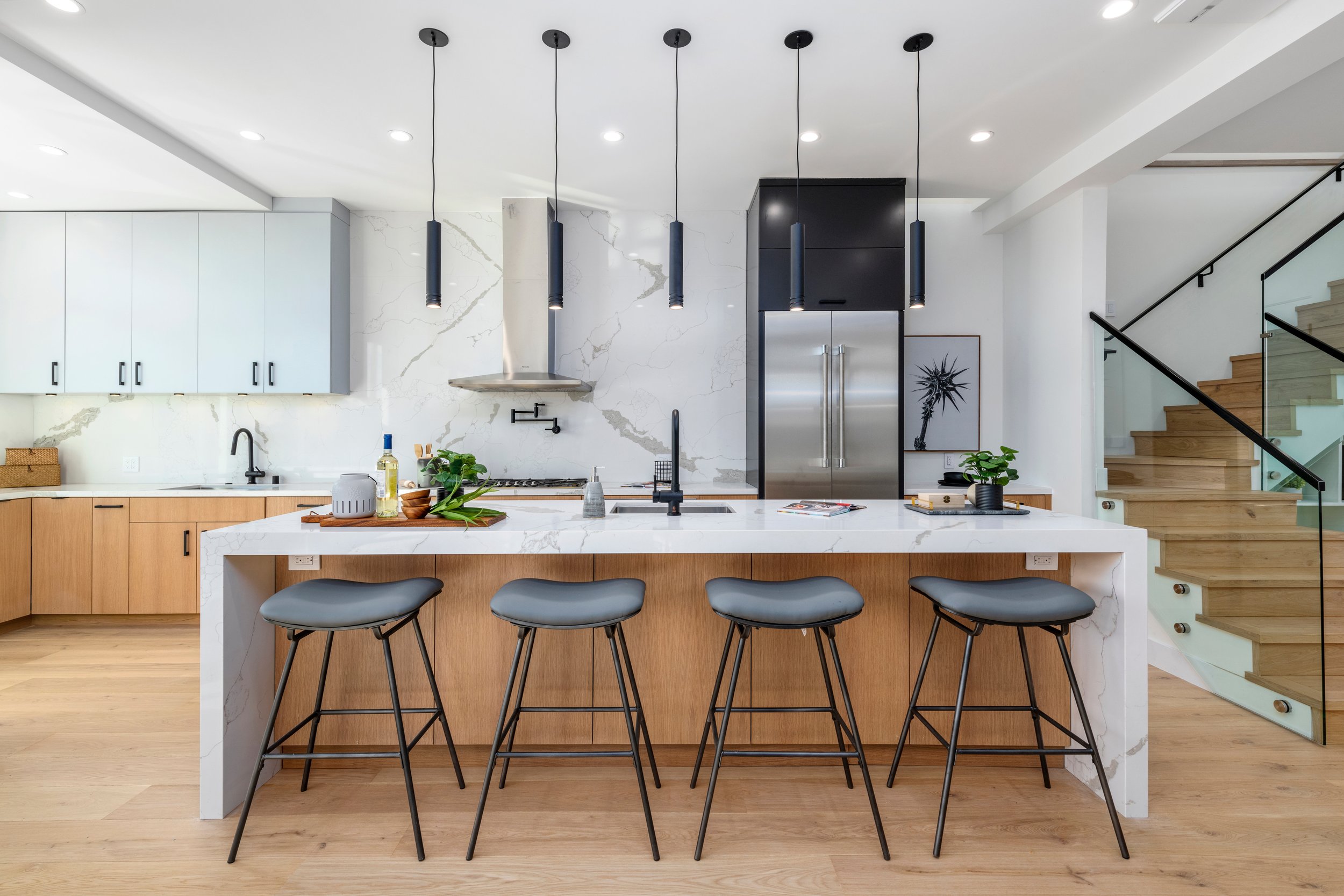 Cocina moderna con isla de mármol, estantes de madera y electrodomésticos de acero inoxidable