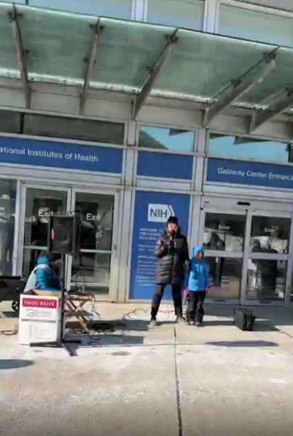 A person speaks at an NIH vigil