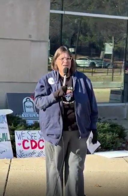 A woman speaks at an NIH vigil