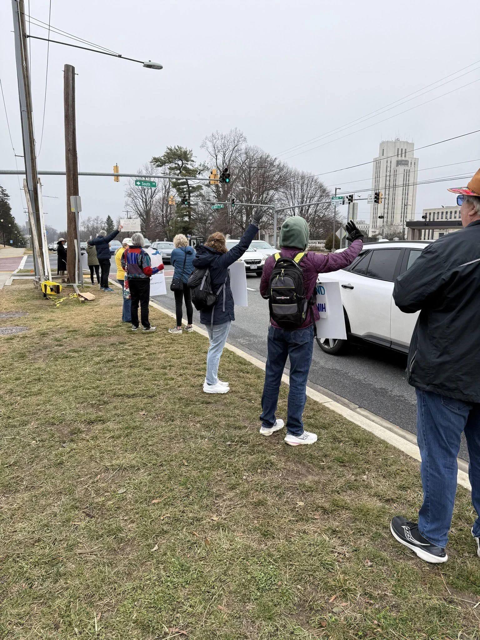 Protestors waving signs by the roadside at the end of the vigil