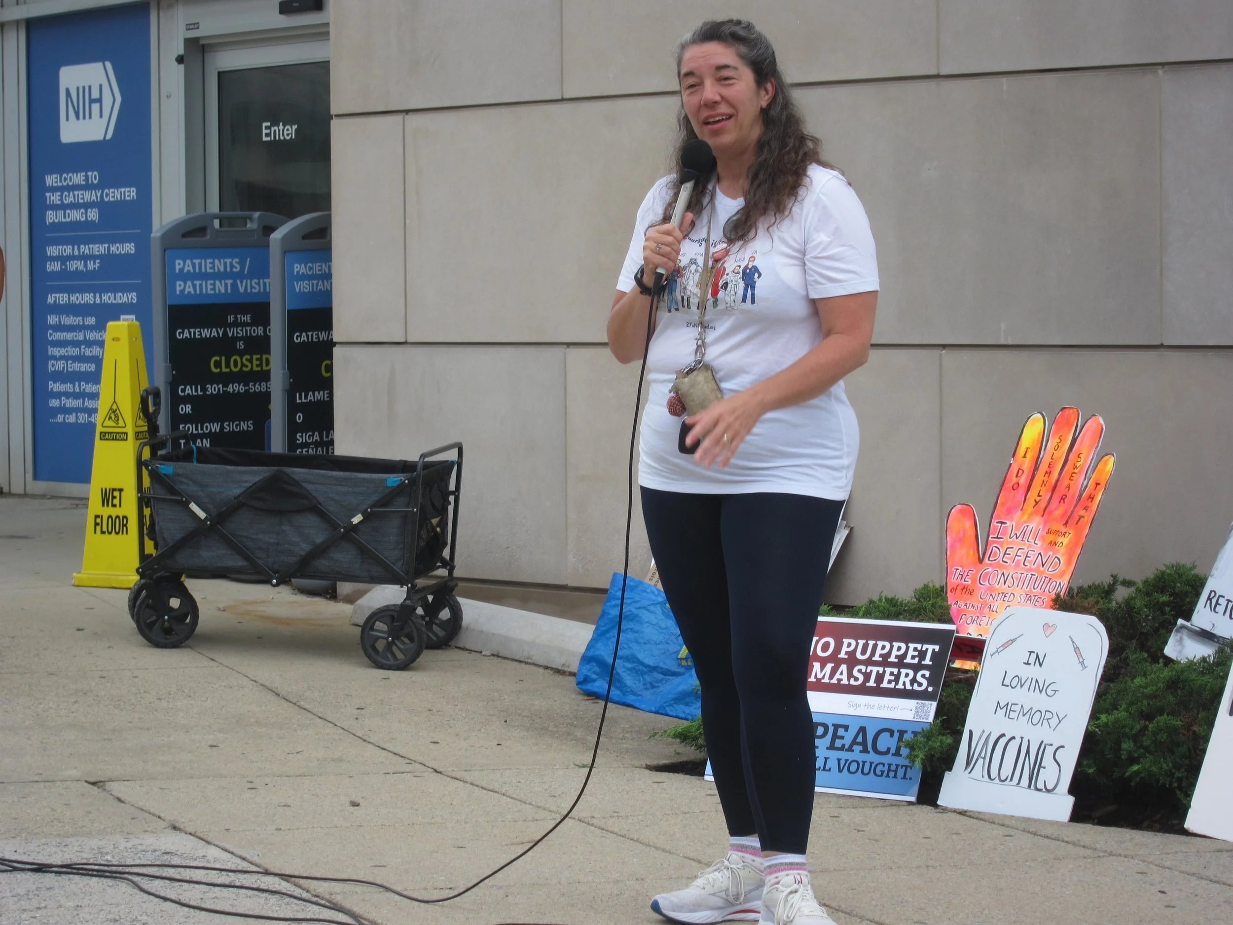 A woman wearing a "Courage is Contagious" shirt speaks into a microphone
