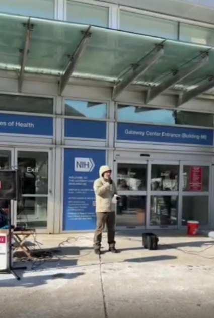 A person speaks at an NIH vigil