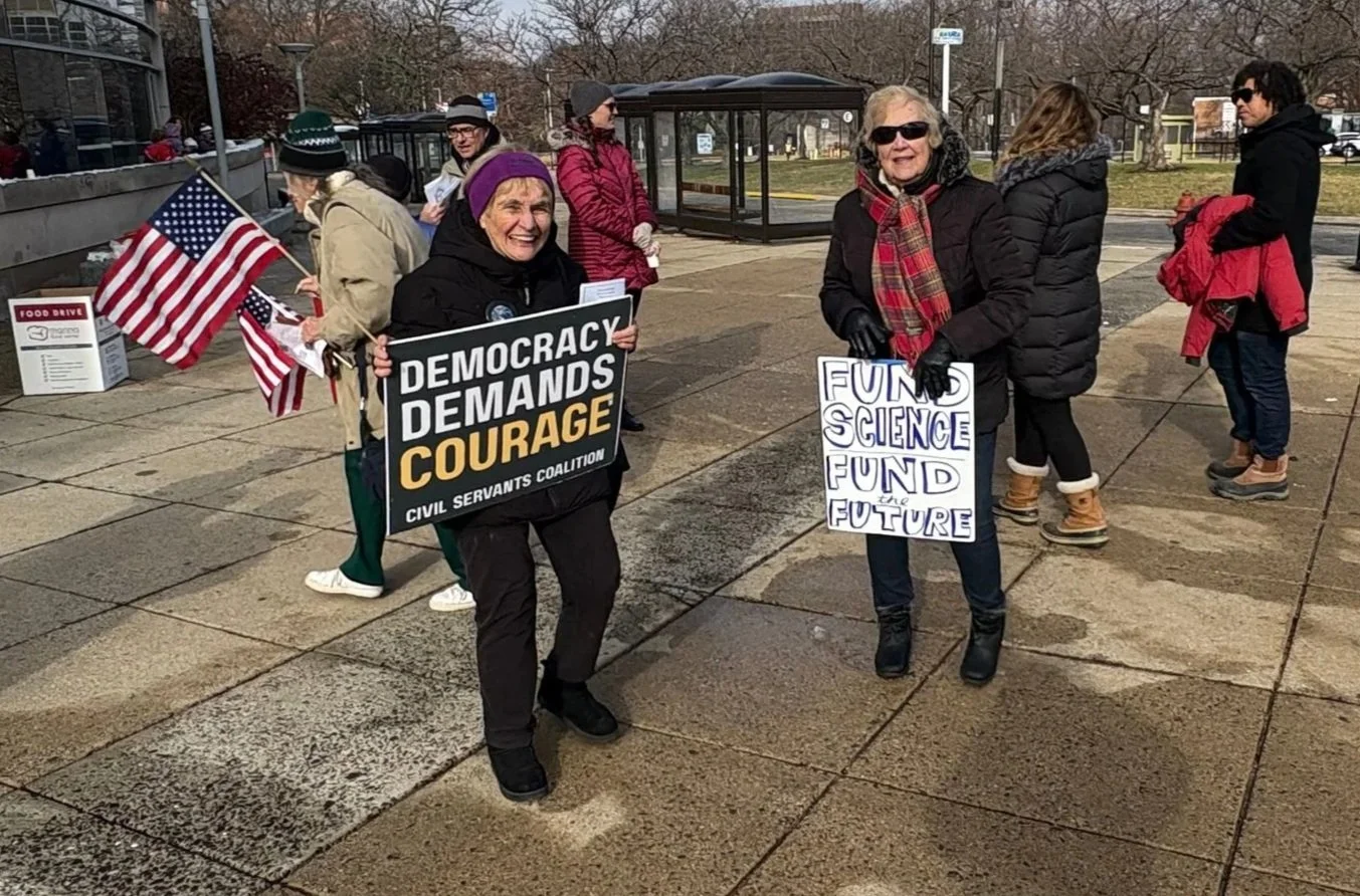 Two women, one holding an American flag and both holding protest signs