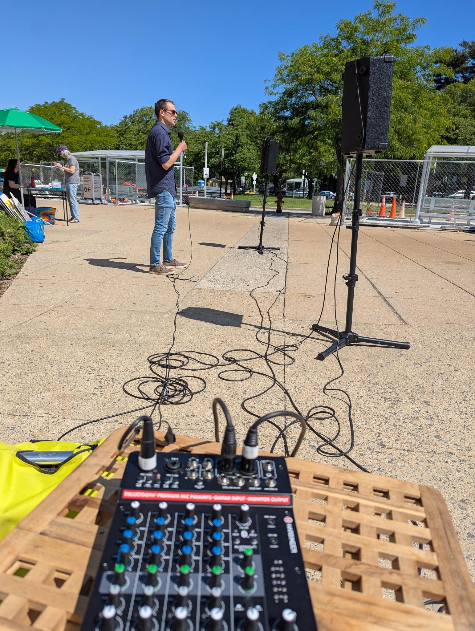 A man speaks at the NIH Vigil with a soundboard in the foreground
