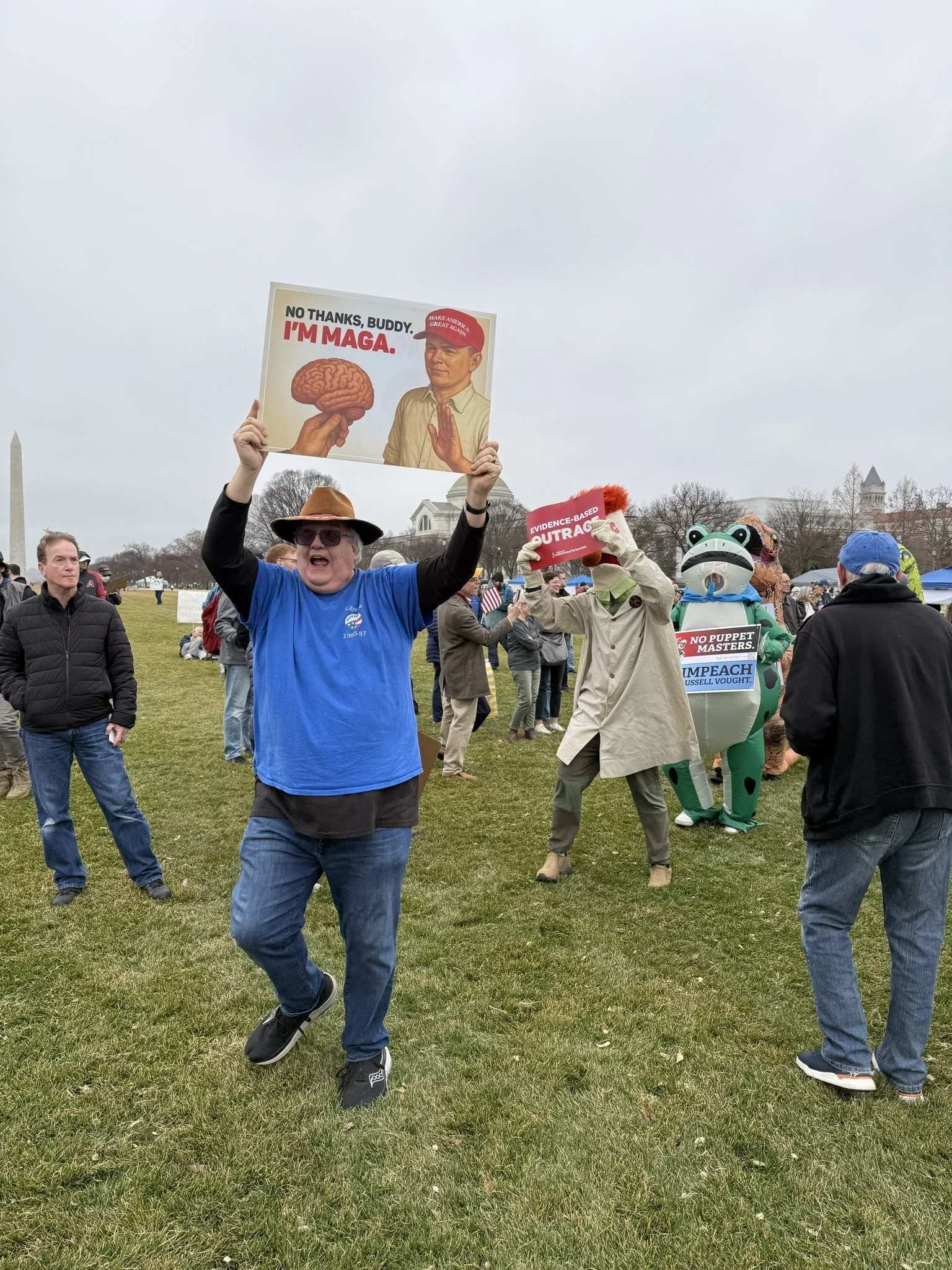 A group of protestors, one in a frog suit, with signs