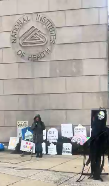 A person speaks at an NIH vigil