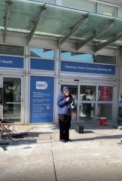 A person speaks at an NIH vigil