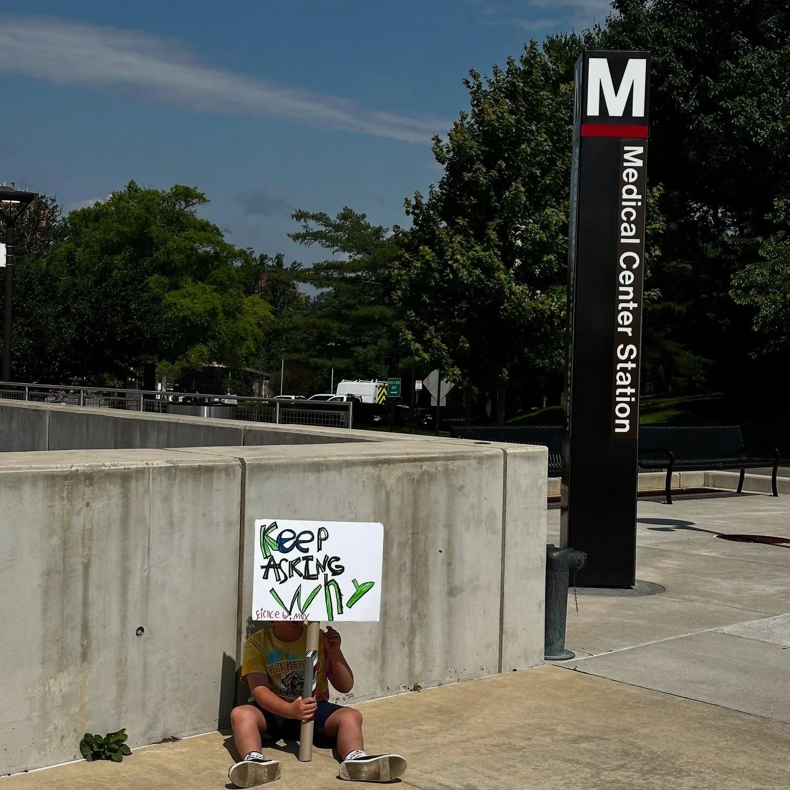 A protestor holds a sign while sitting near the Medical Center Metro entrance