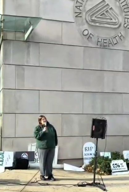 A woman speaks at an NIH vigil