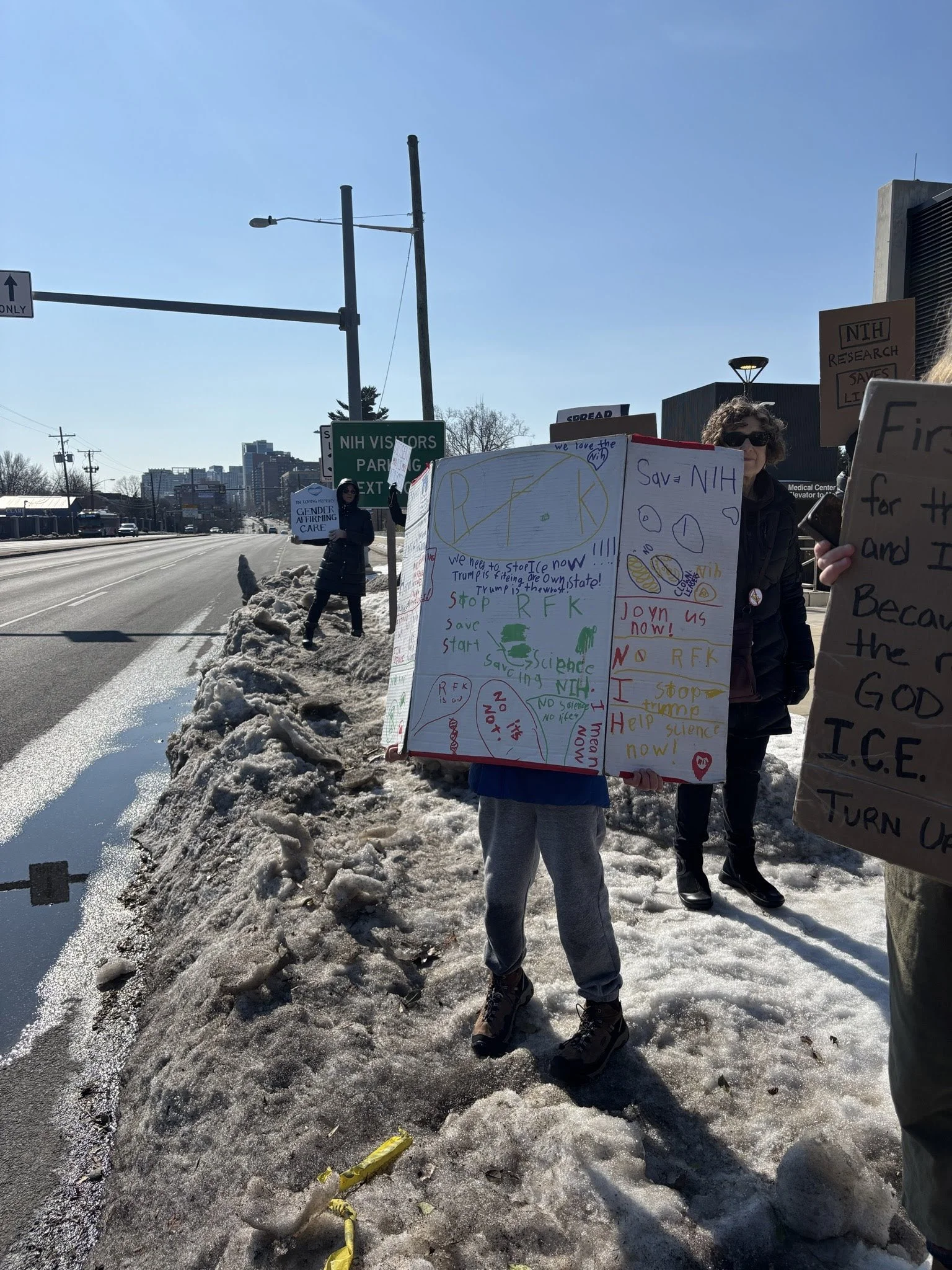 A person holding a protest sign by the roadside