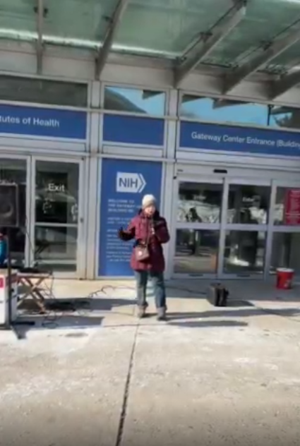 A person speaks at an NIH vigil