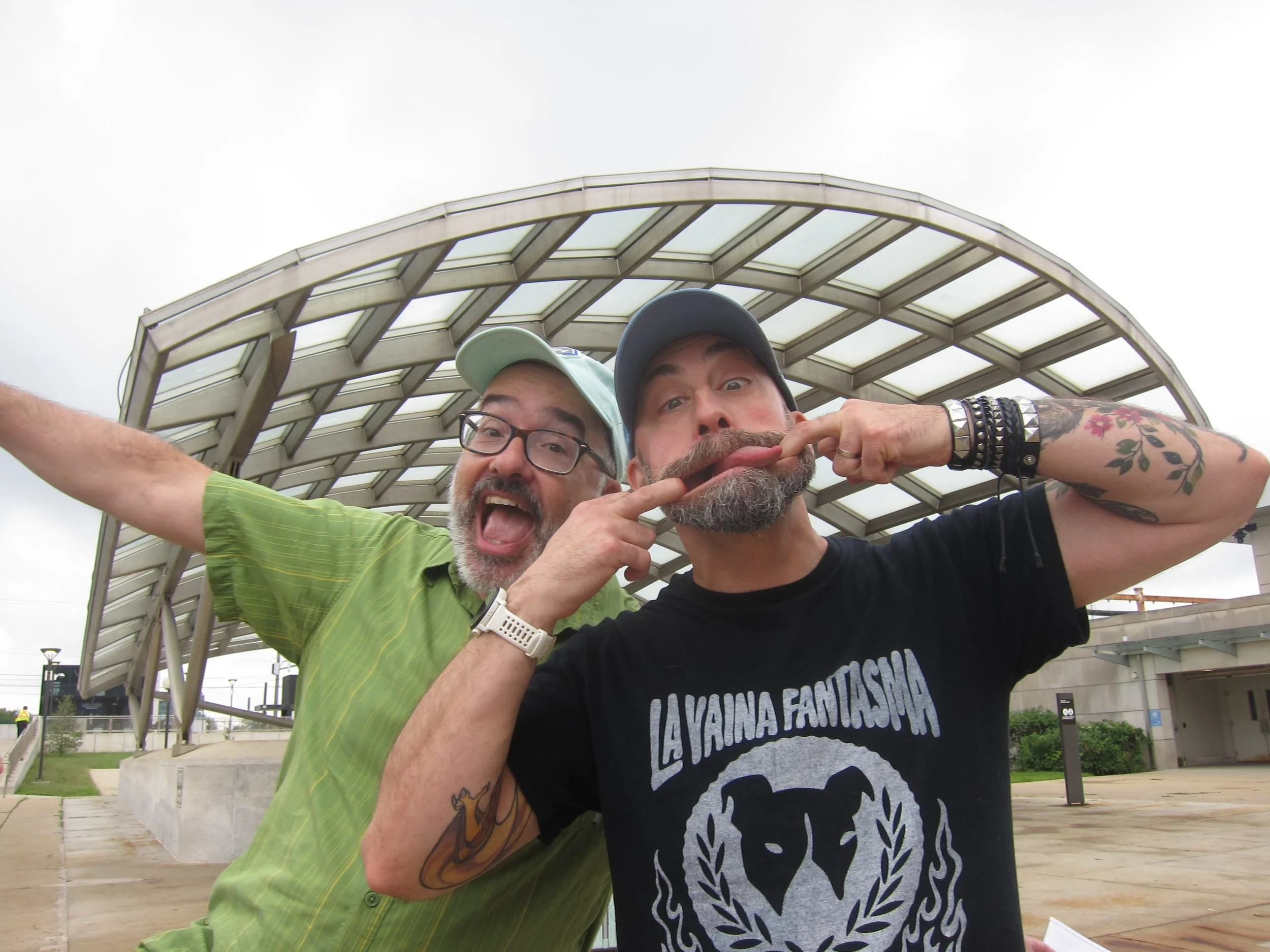 A man pulls a funny face at the camera while another man photobombs him