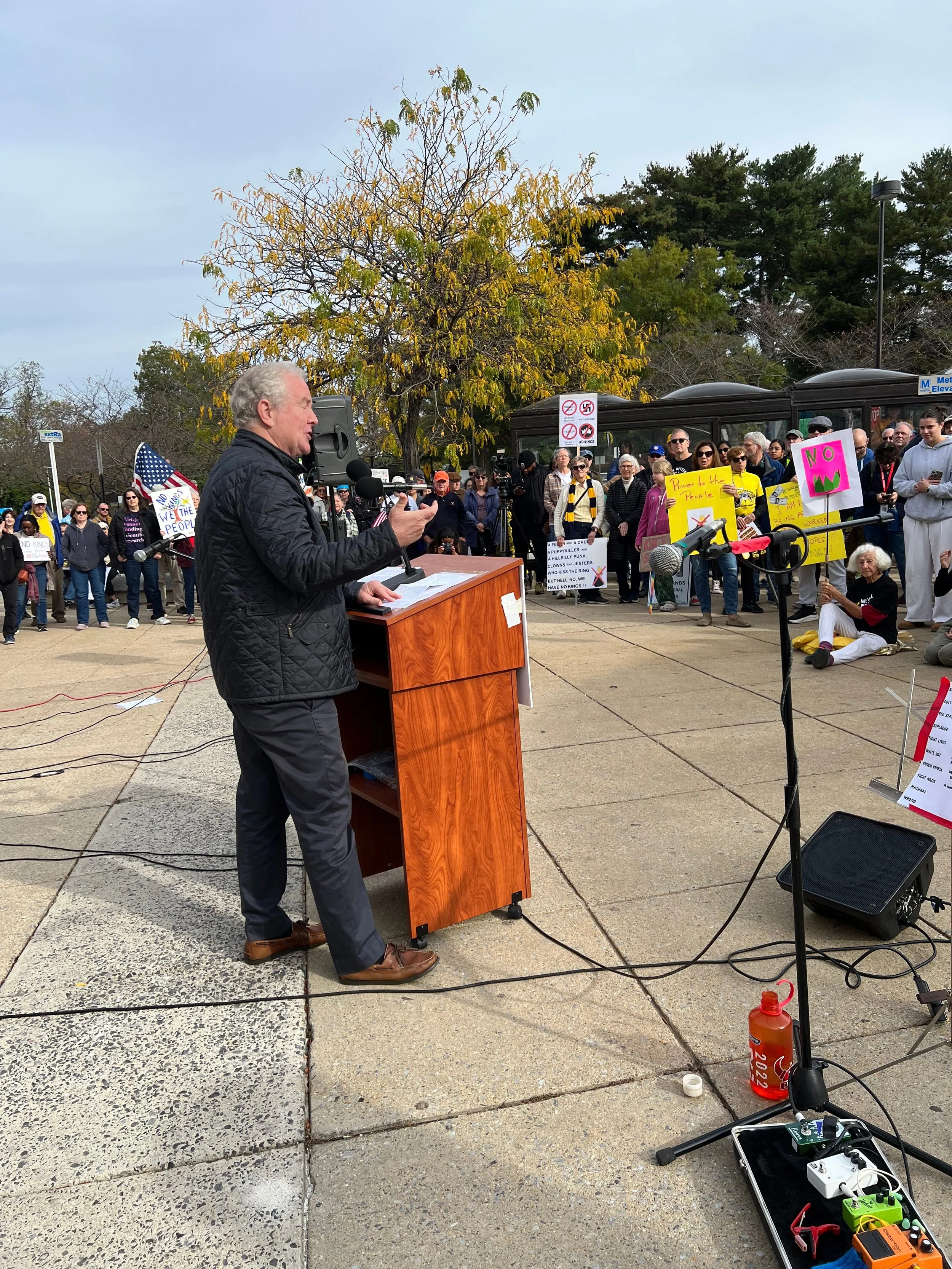 A man stands at a podium, talking to a group of people, during one of the 27 UNIHTED Community Vigils.