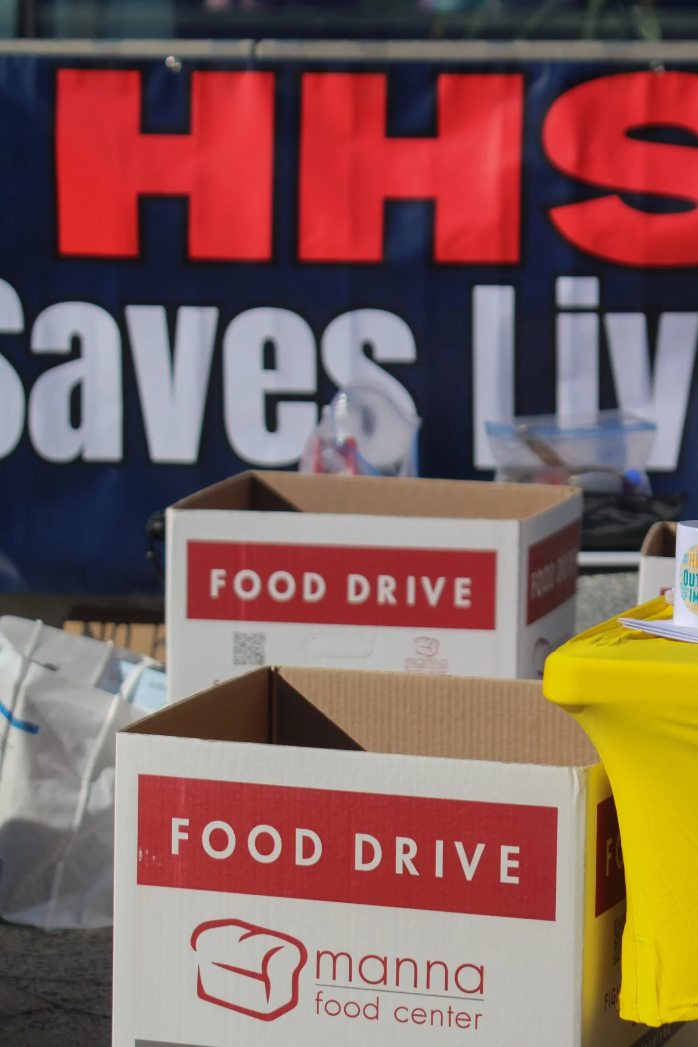 Food drive boxes in front of an "HHS Saves Lives" banner