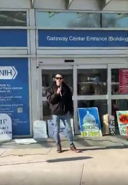A person speaking at an NIH vigil