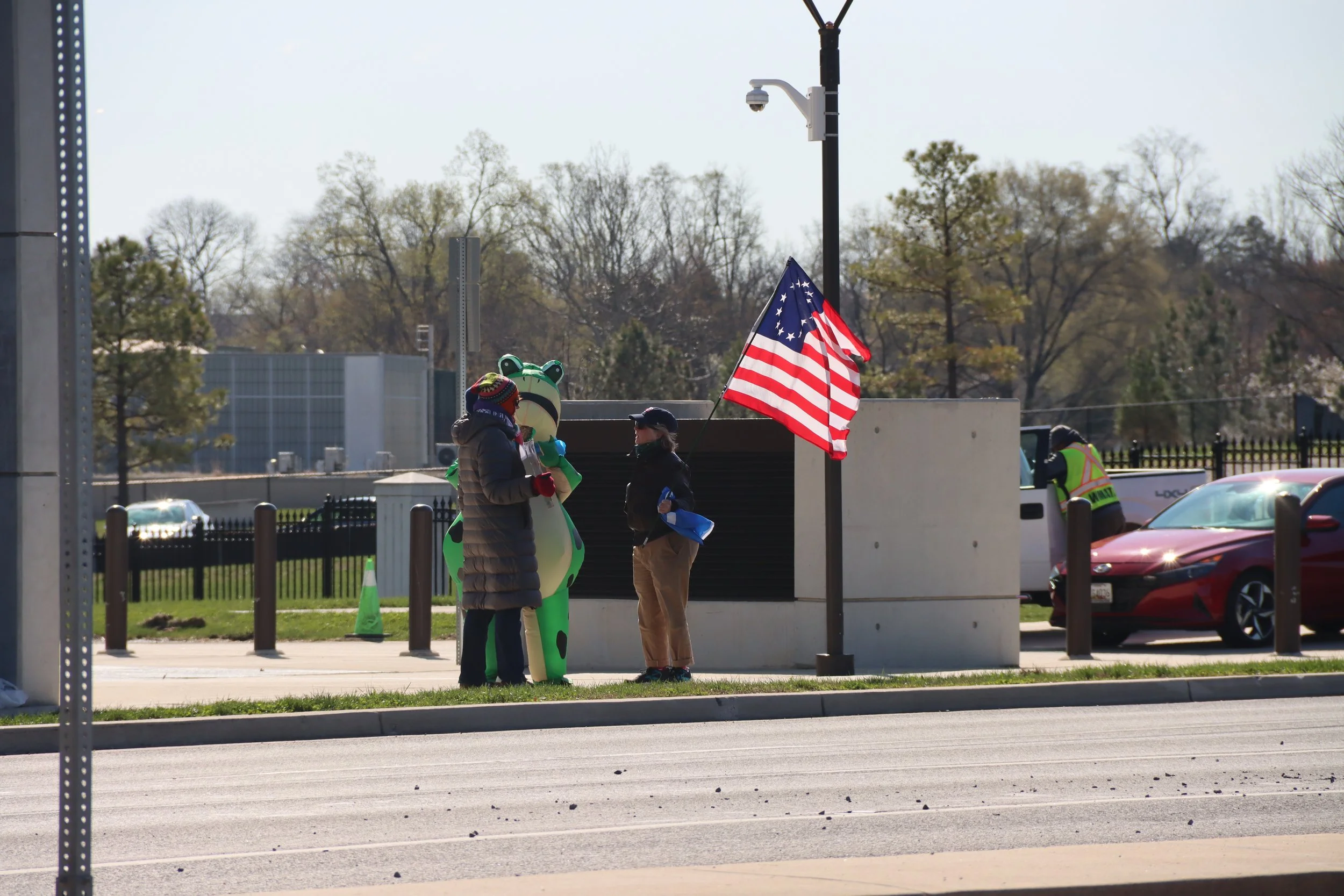 Roadside protestors, including one in a flag costume and another holding an old flag