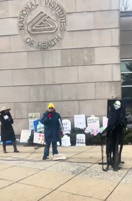 A person speaks at an NIH vigil