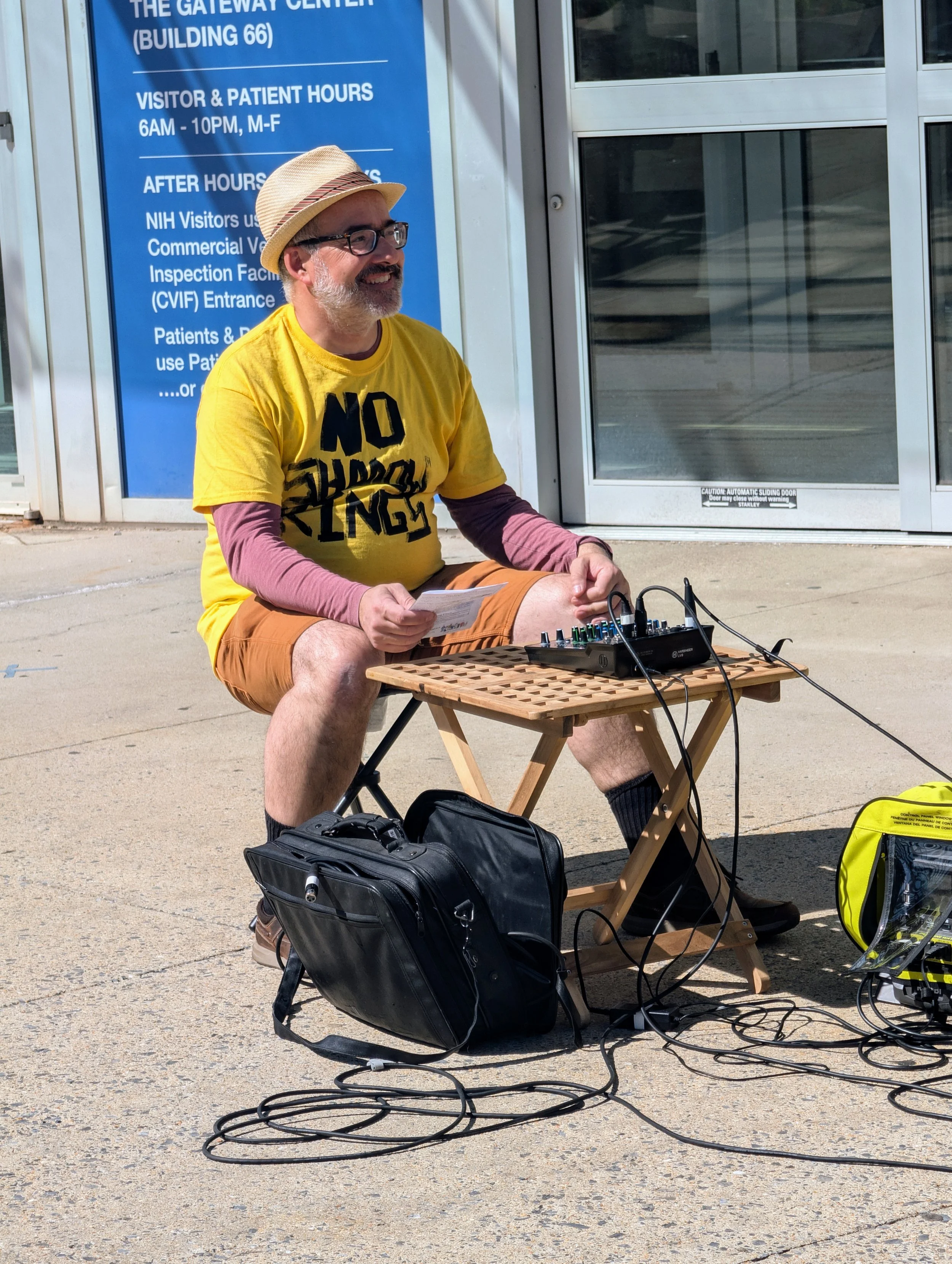 A smiling man in a No Shadow Kings t-shirt sits at the soundboard