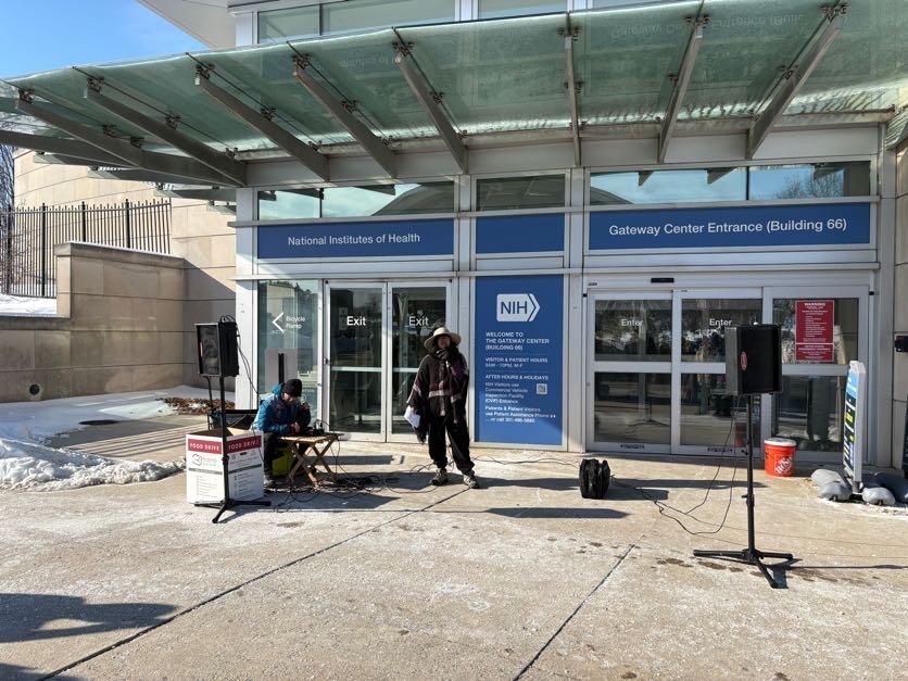 A person speaks at an NIH vigil
