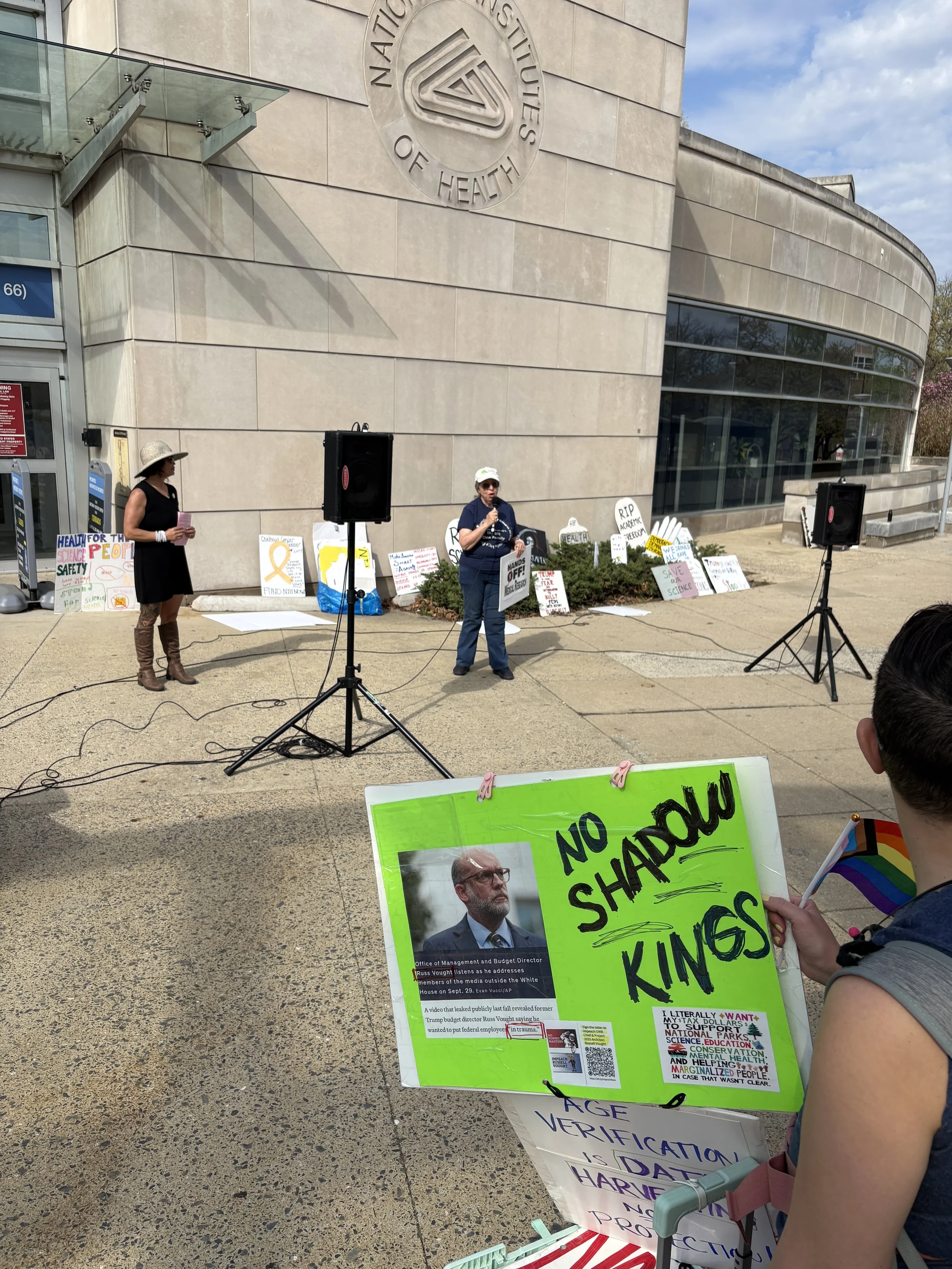 A person holding a "no shadow kings" sign watches the vigil