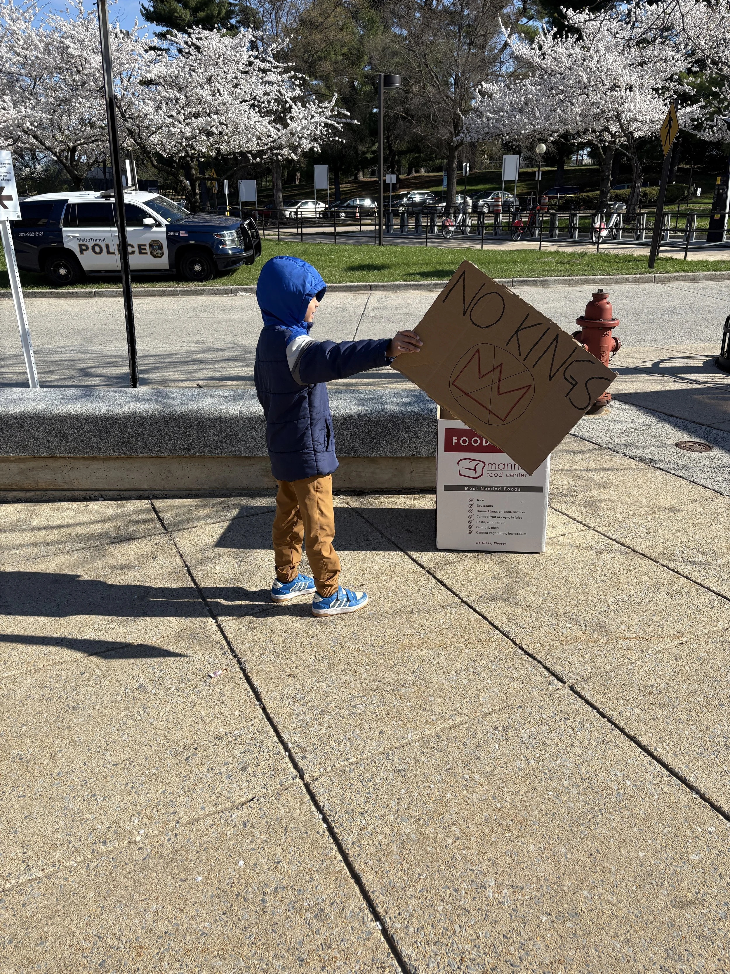 A child holding a "no Kings" protest sign