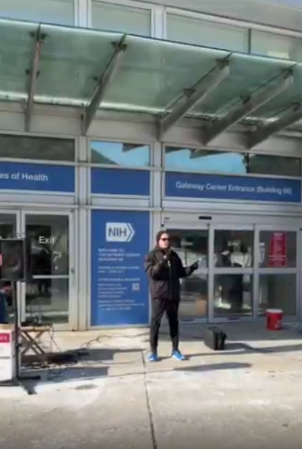 A person speaks at an NIH vigil