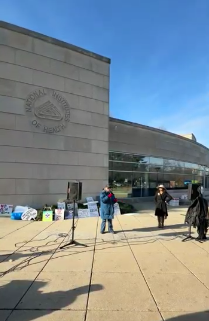 A person speaks at an NIH vigil