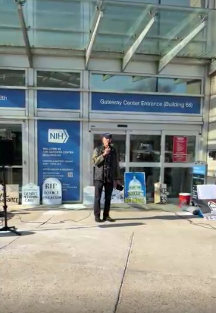 A person speaking at an NIH vigil