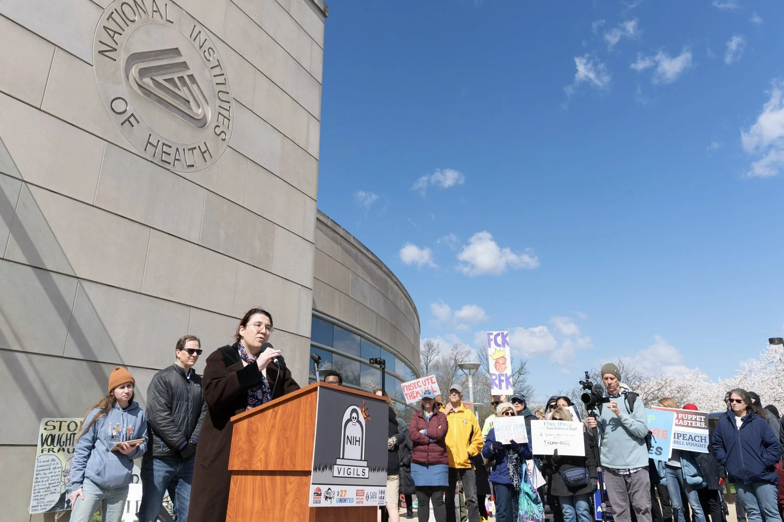 A woman speaks below the NIH logo