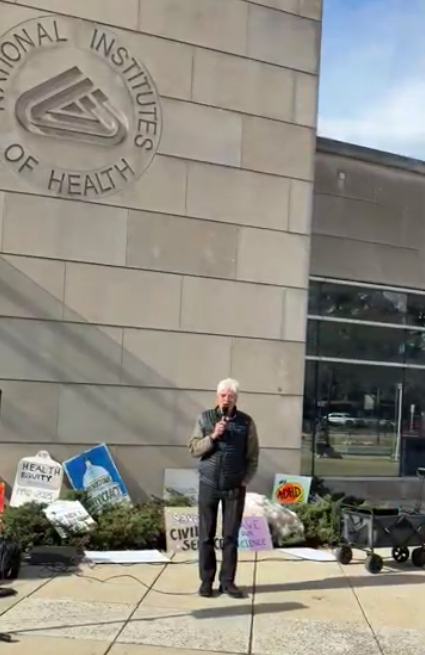 A person speaks at an NIH vigil