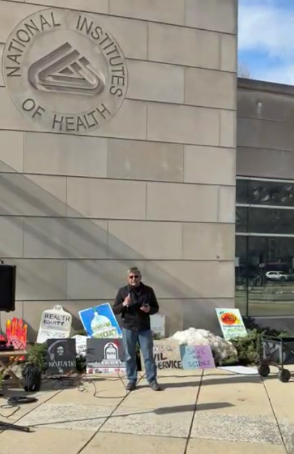 A person speaks at an NIH vigil