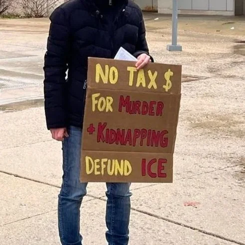 A protest sign reading "No tax $ for murder + kidnapping, defund ICE"