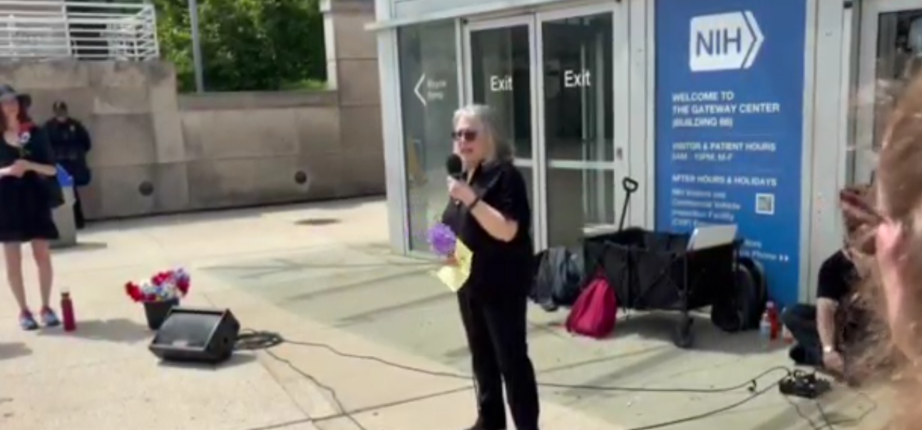 A woman speaks into the microphone at an NIH vigil