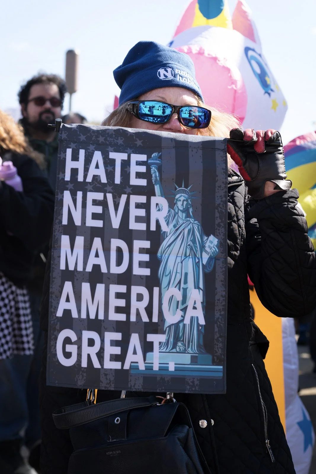 A person holds a protest sign that says "Hate never made America great"