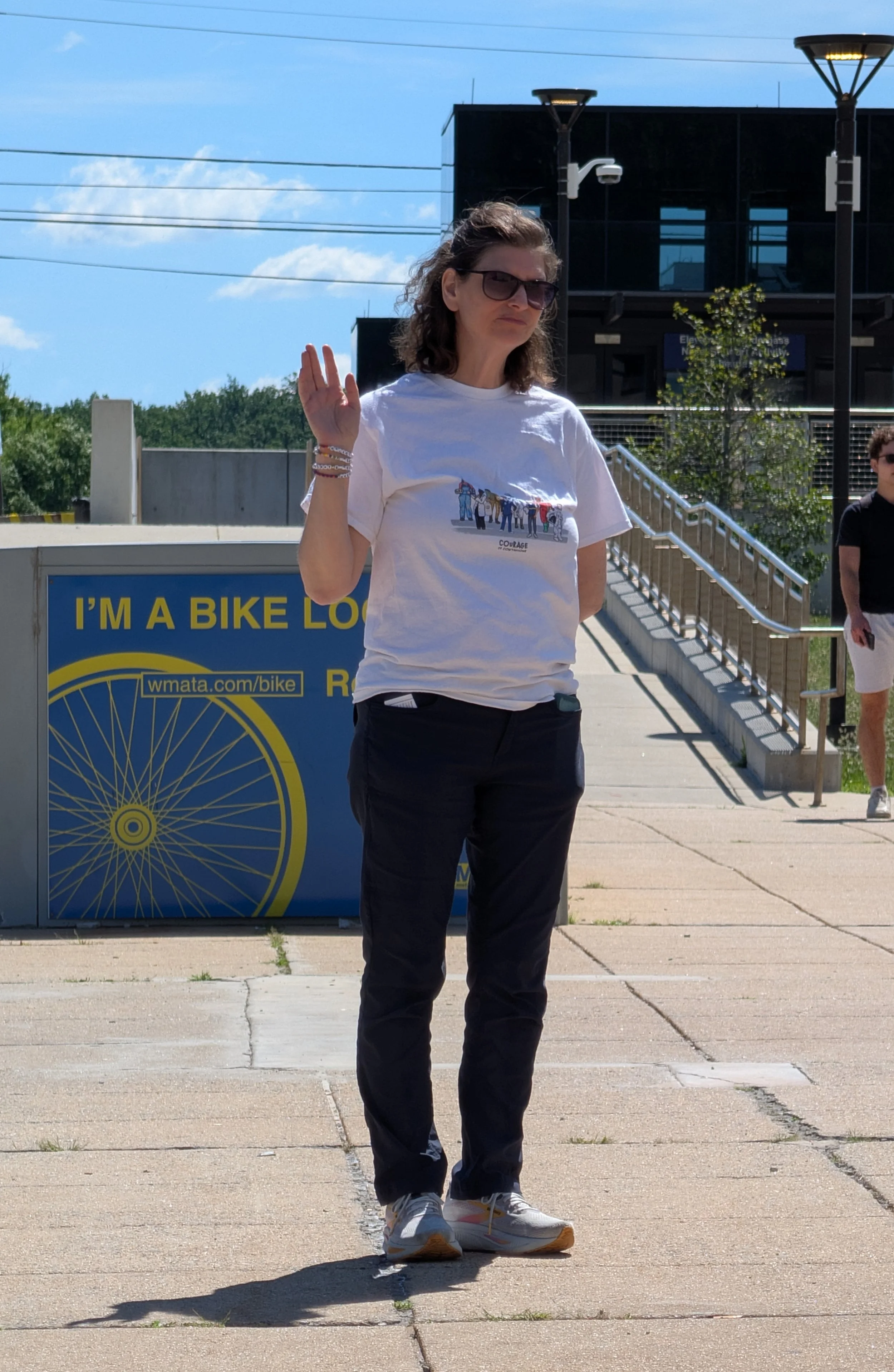 An NIH Vigil attendee raises a hand for the oath while standing near the Metro bike lockers.