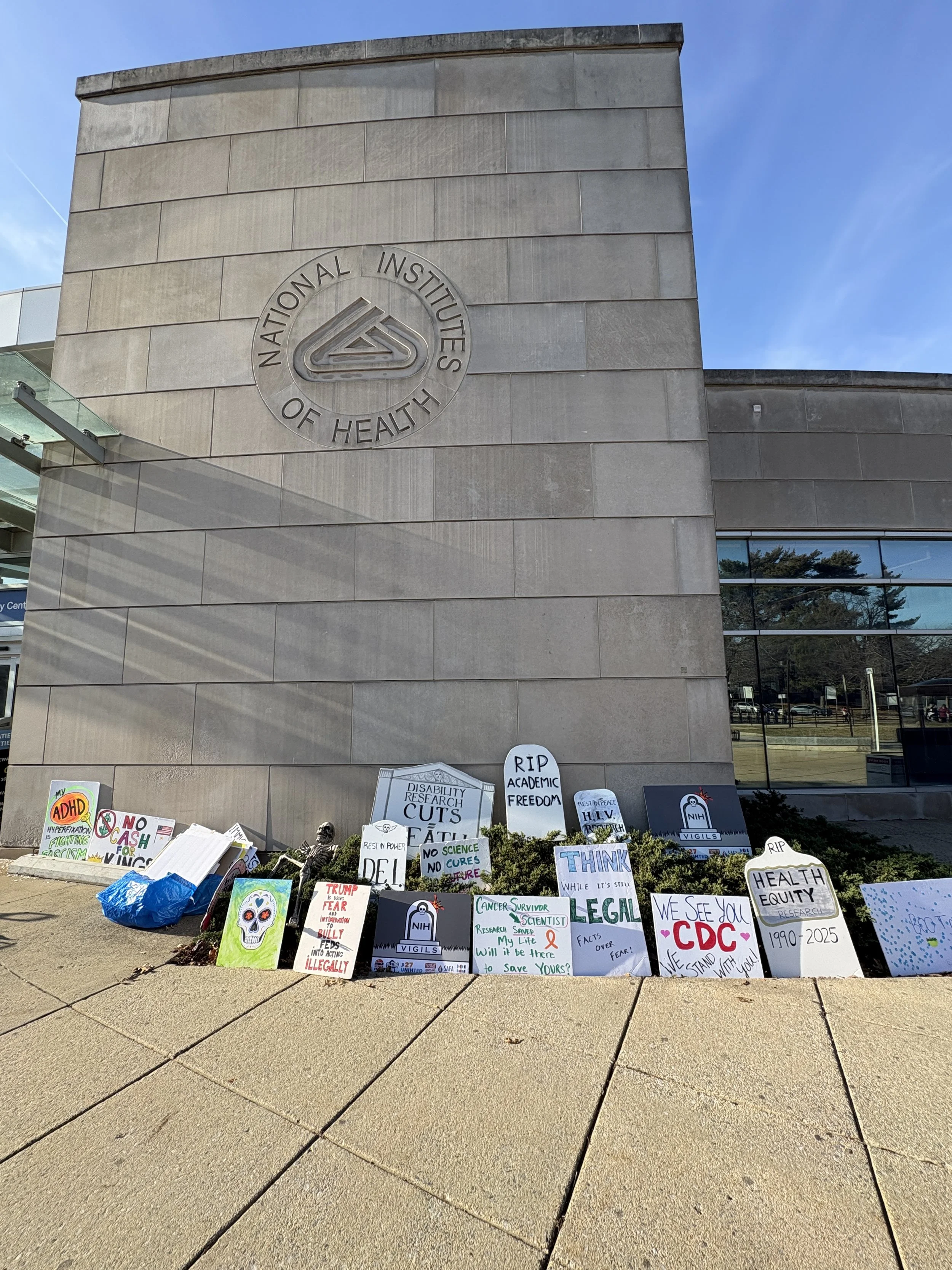 Tombstone-shaped protest signs outside NIH