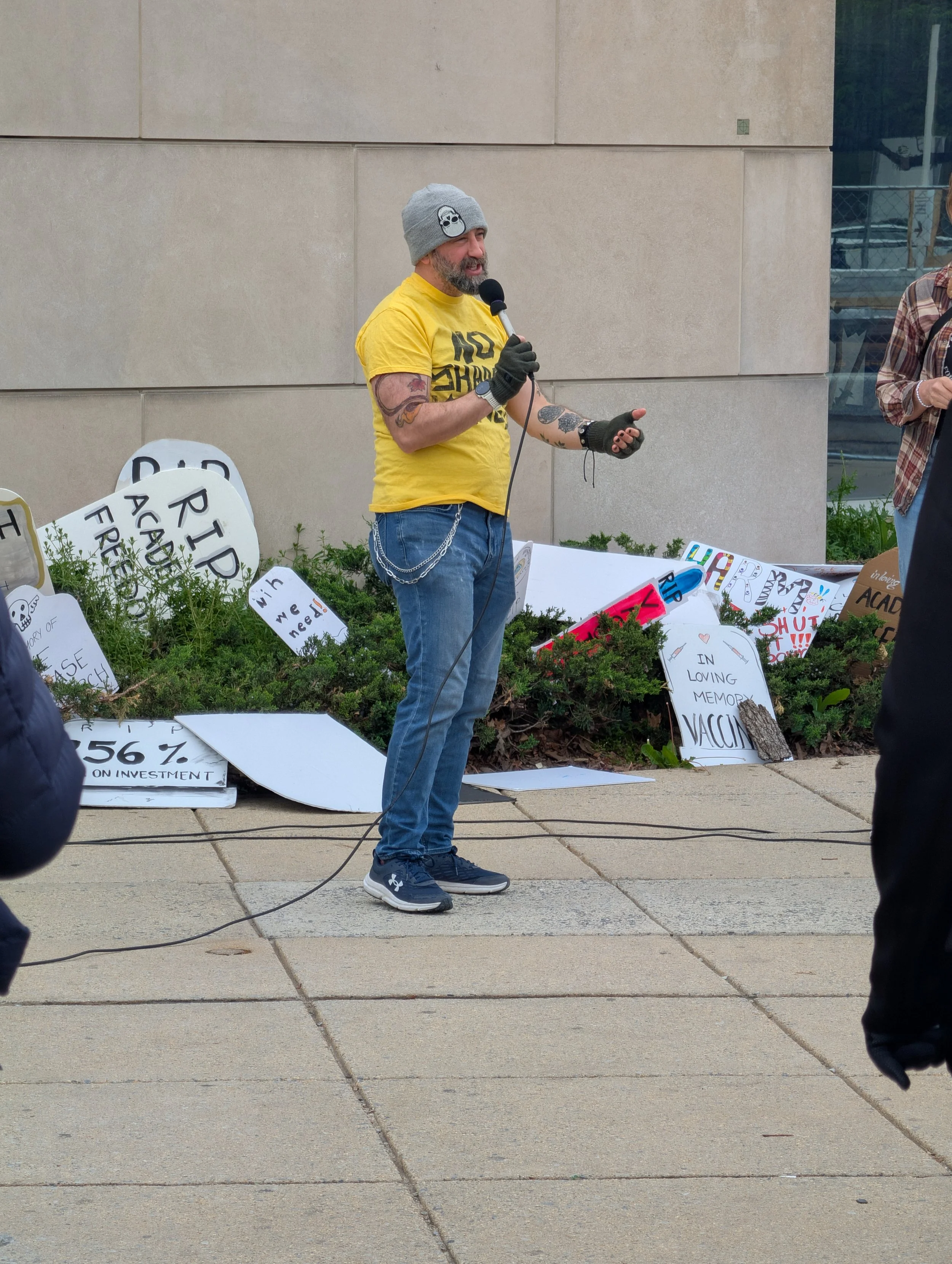 A man with a yellow shirt speaking at the vigil