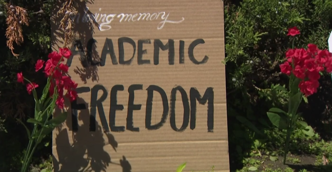 A tombstone-shaped protest signs with flowers
