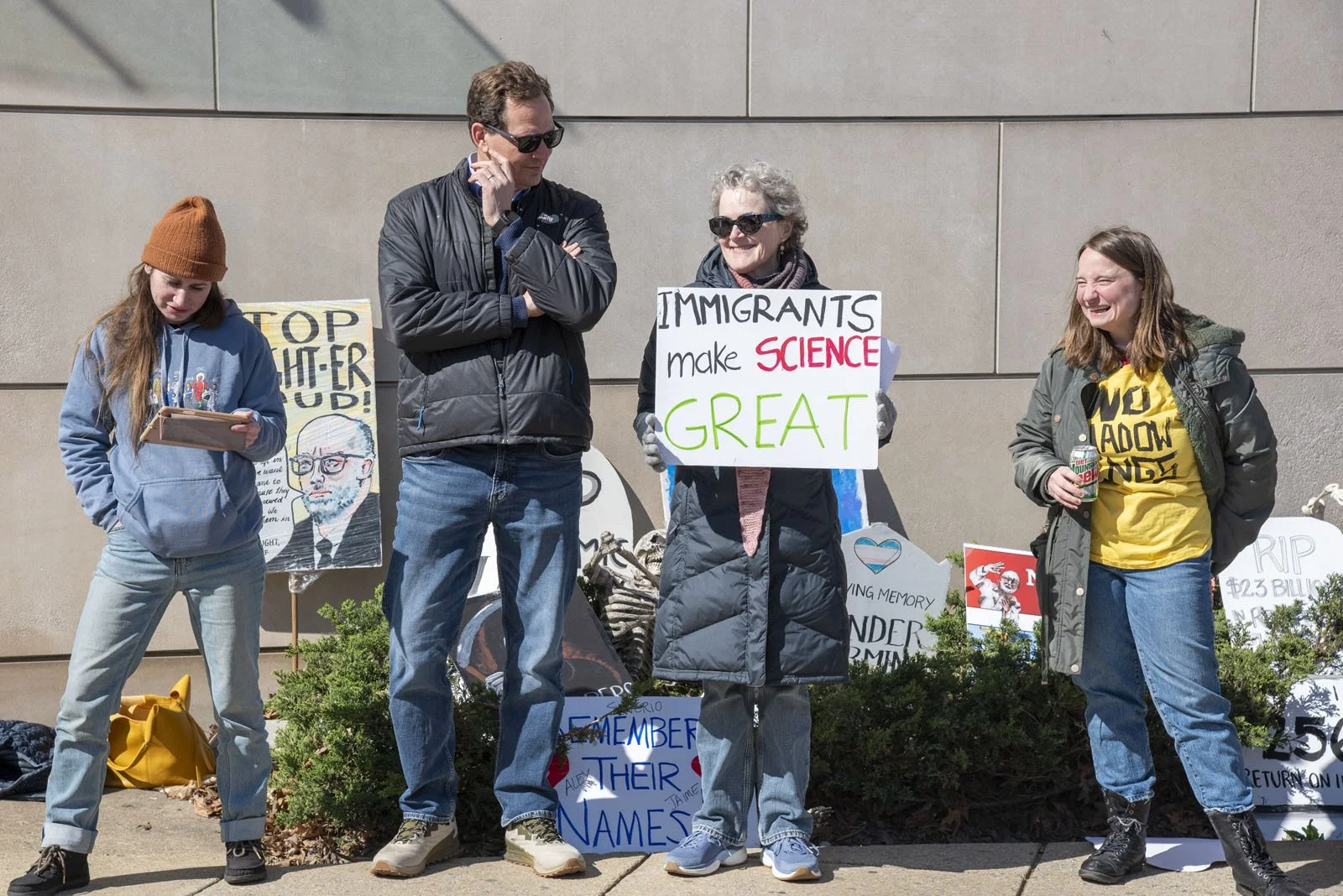 Four people standing in front of the "graveyard" of tombstone-shaped protest signs