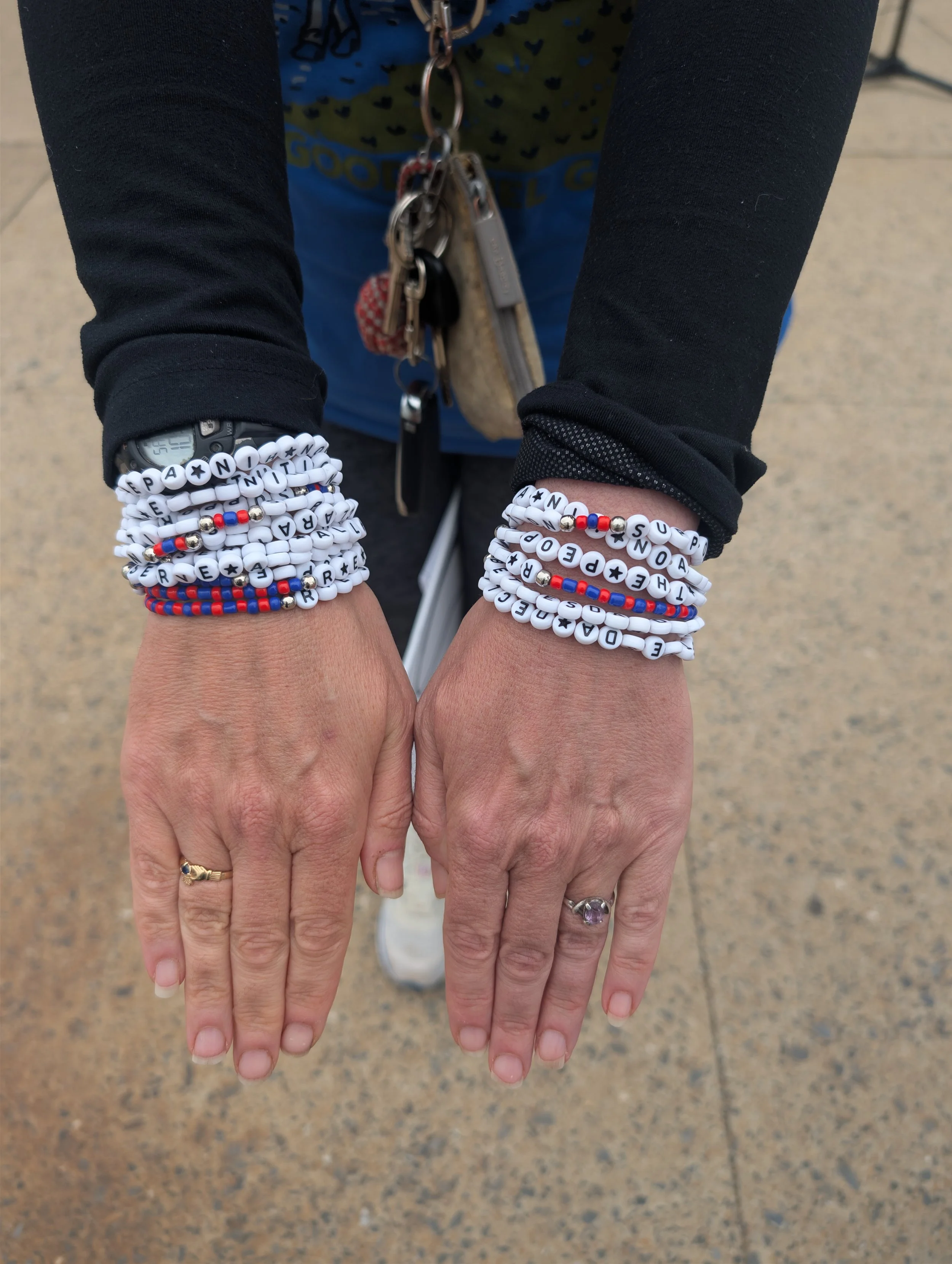 The hands of a person wearing a multiple science-themed friendship bracelets