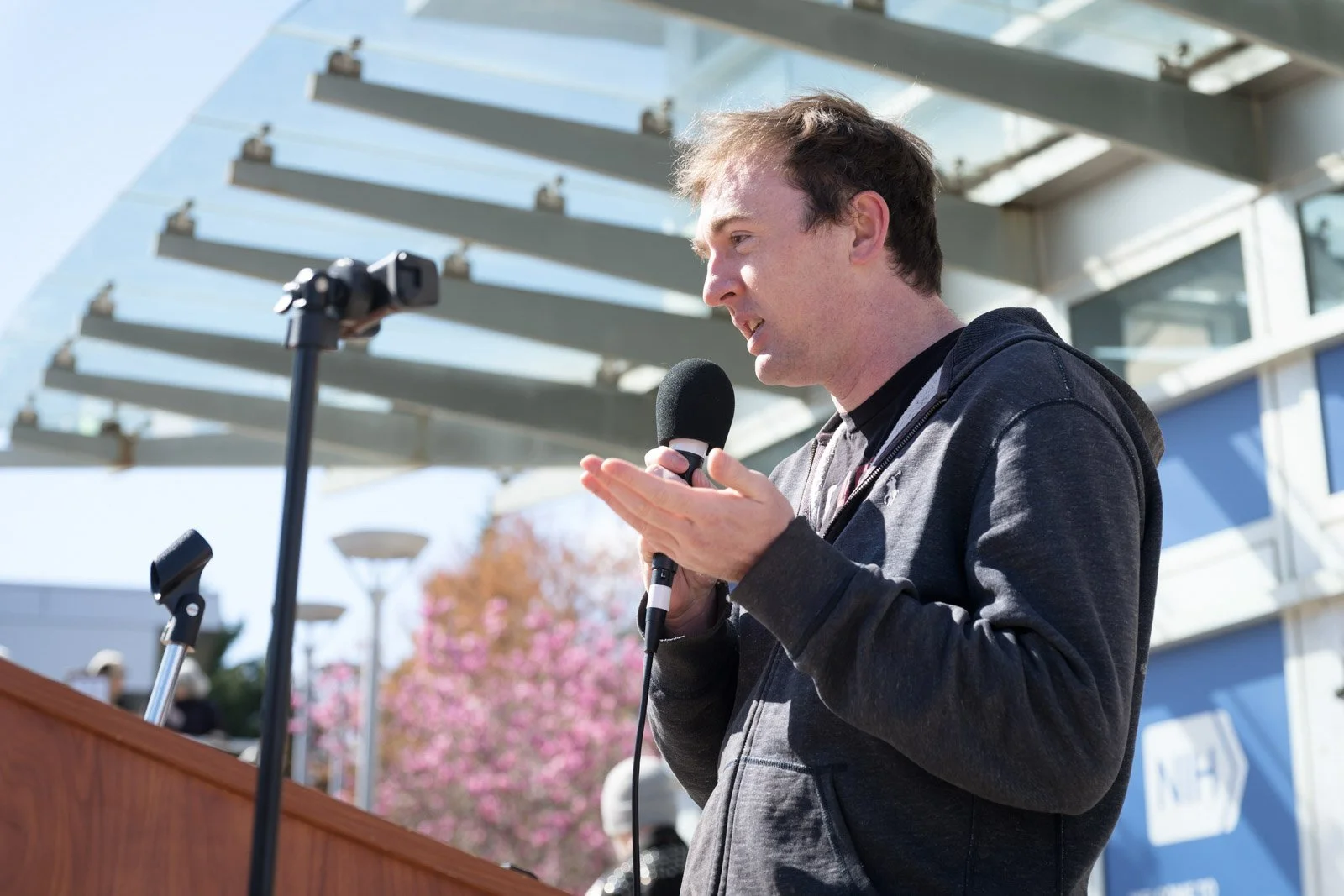 A man gestures while speaking into a microphone