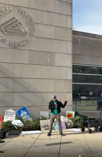 A person speaks at an NIH vigil
