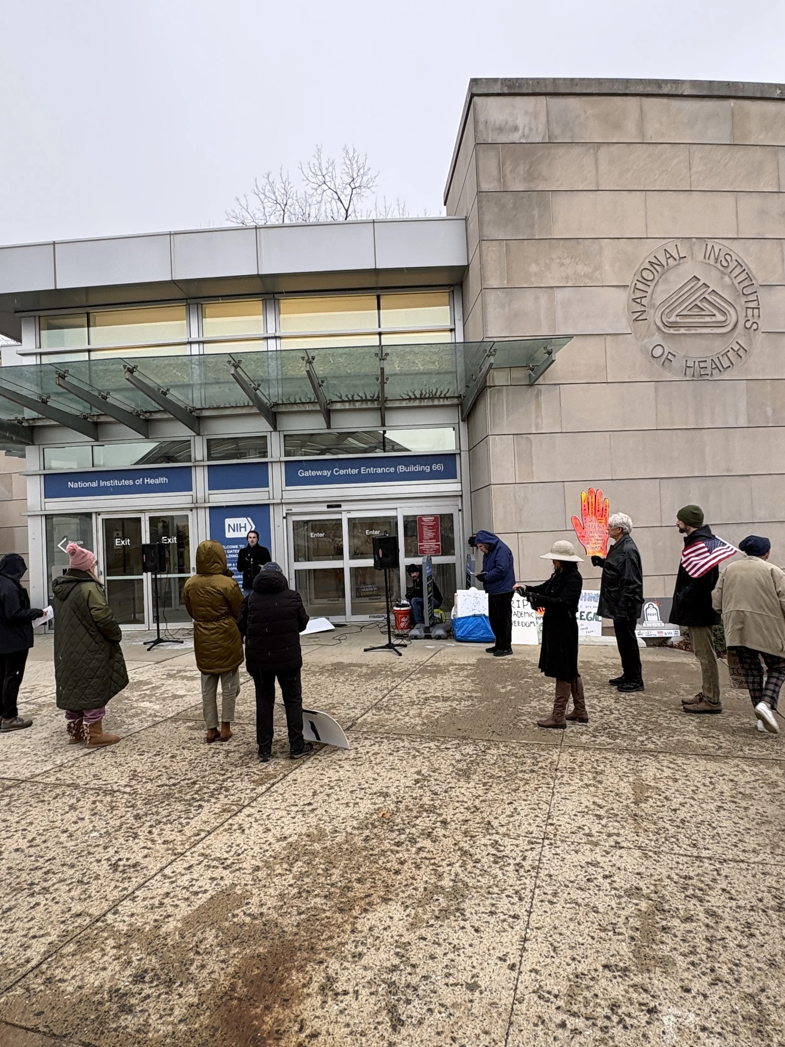 A small crowd of people at a wintry NIH vigil