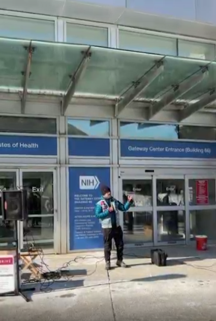 A person speaks at an NIH vigil