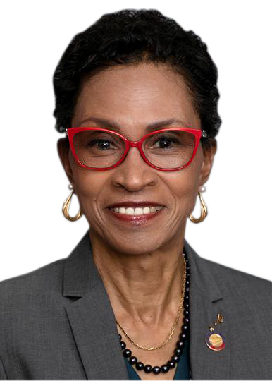 Rep. Renee Price, smiling, wearing red glasses, gold hoop earrings, a gray suit jacket, and a pin on her lapel.