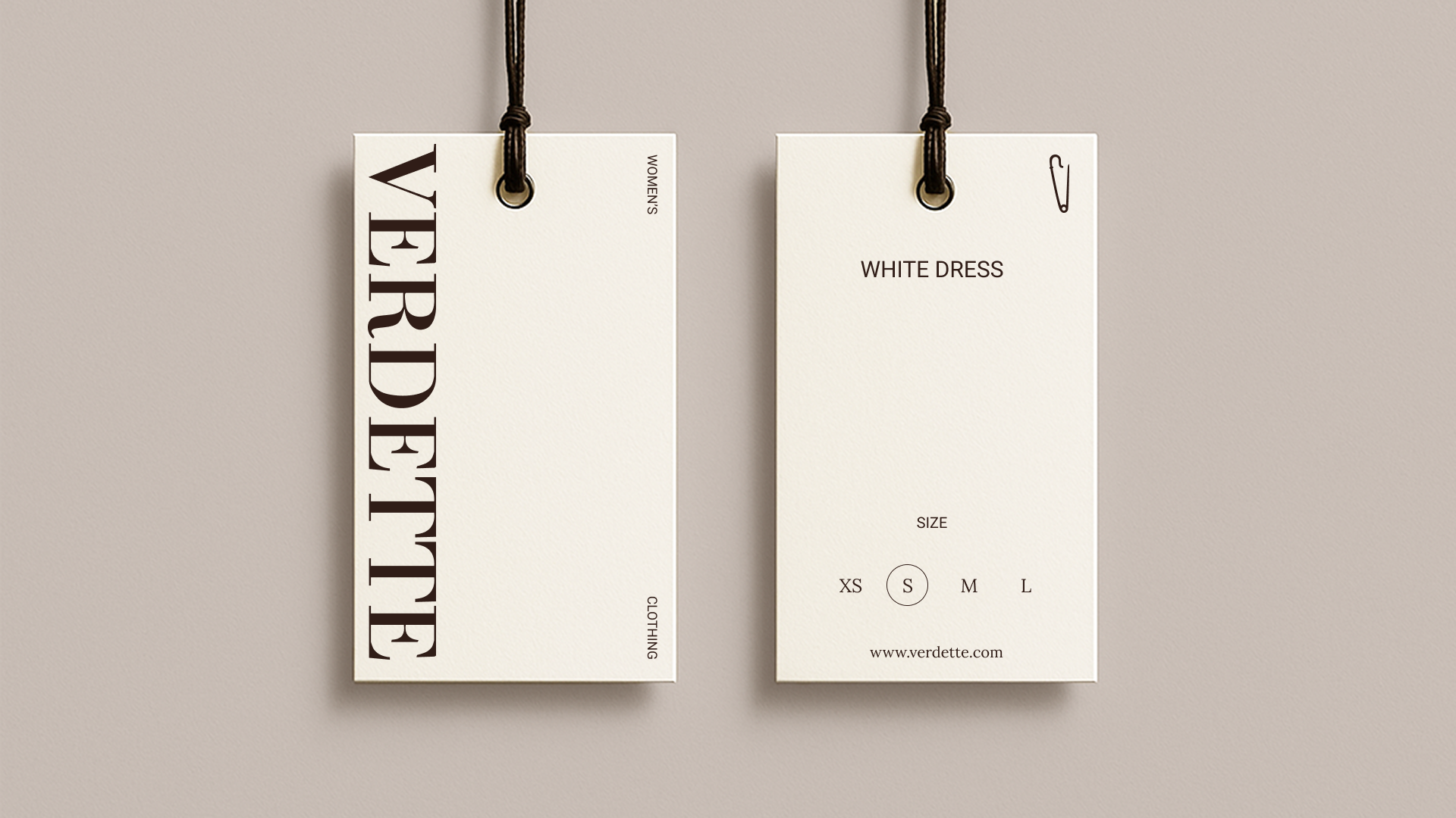 Clothing tags for a women's white dress, size small, with website www.verdette.com, tied to a wall with black string.
