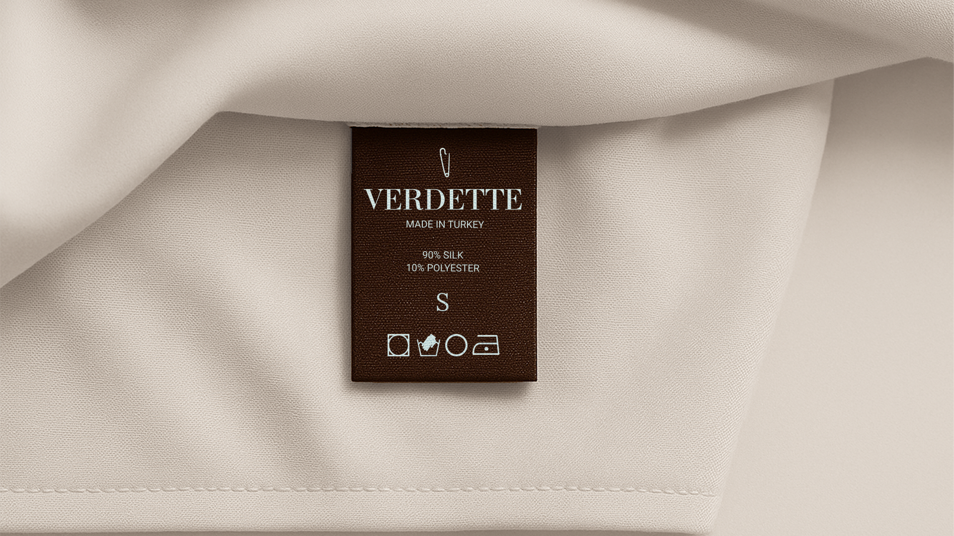 Clothing label on a beige fabric indicating the brand Verdette