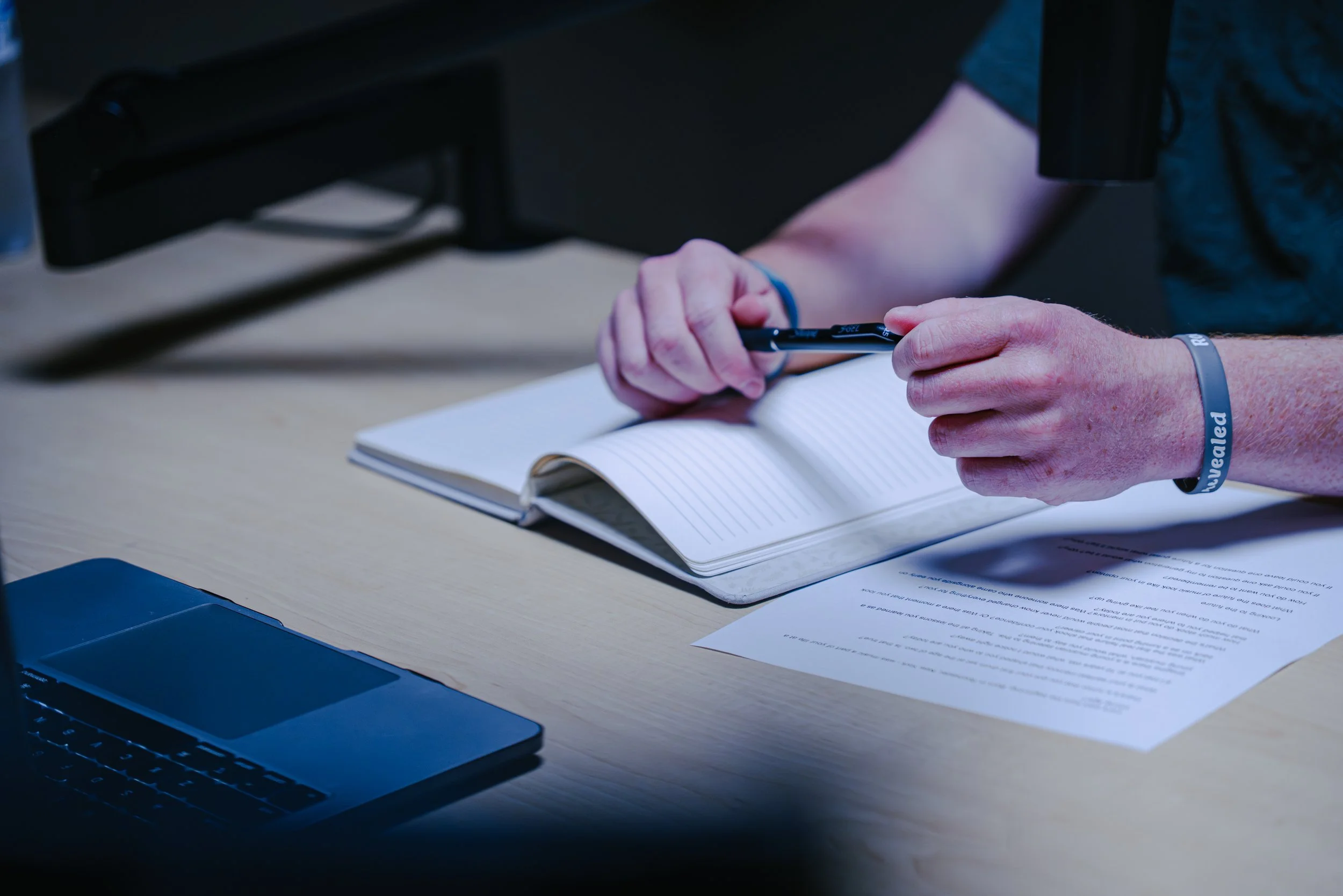 Scenic landscape with mountains, a river, and rolling hills under a cloudy sky.