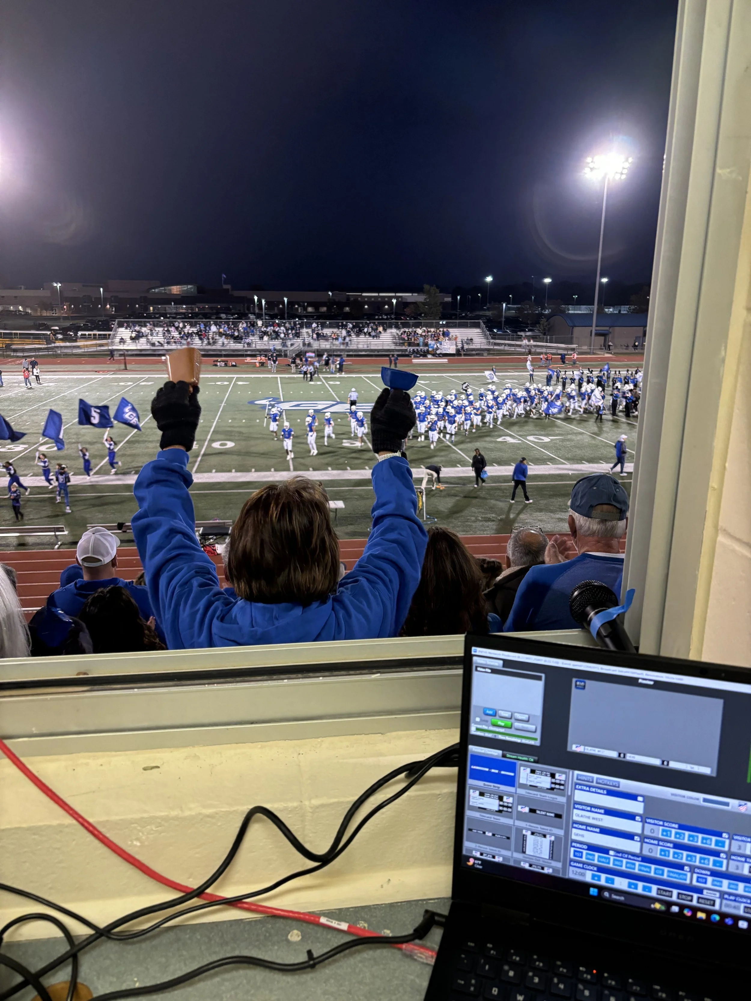 Scenic landscape with a turquoise lake, rolling grassy hills, and rugged mountains in the background under cloudy skies.