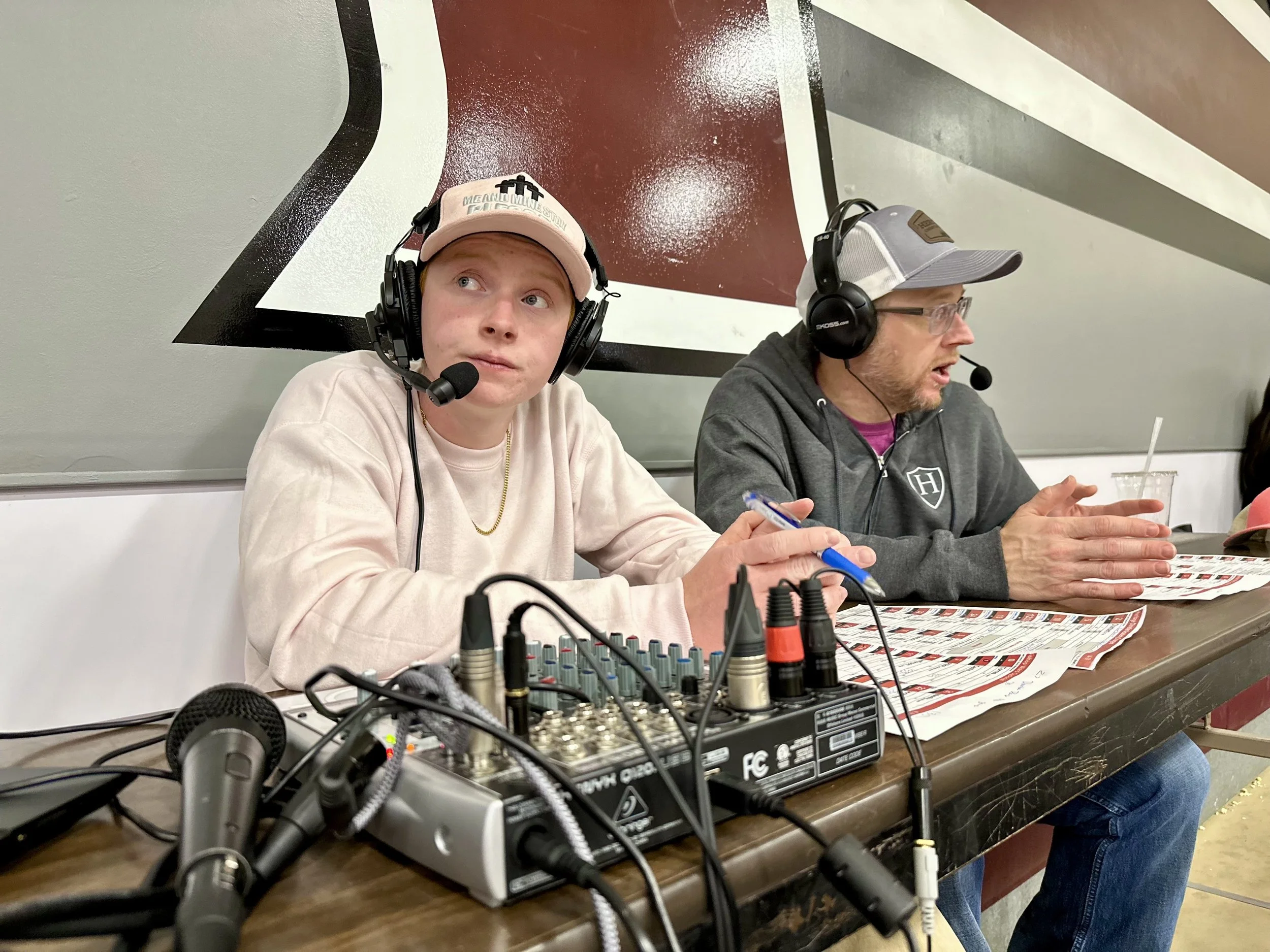 A modern building on a grassy hill with the snow-capped mountains in the background.